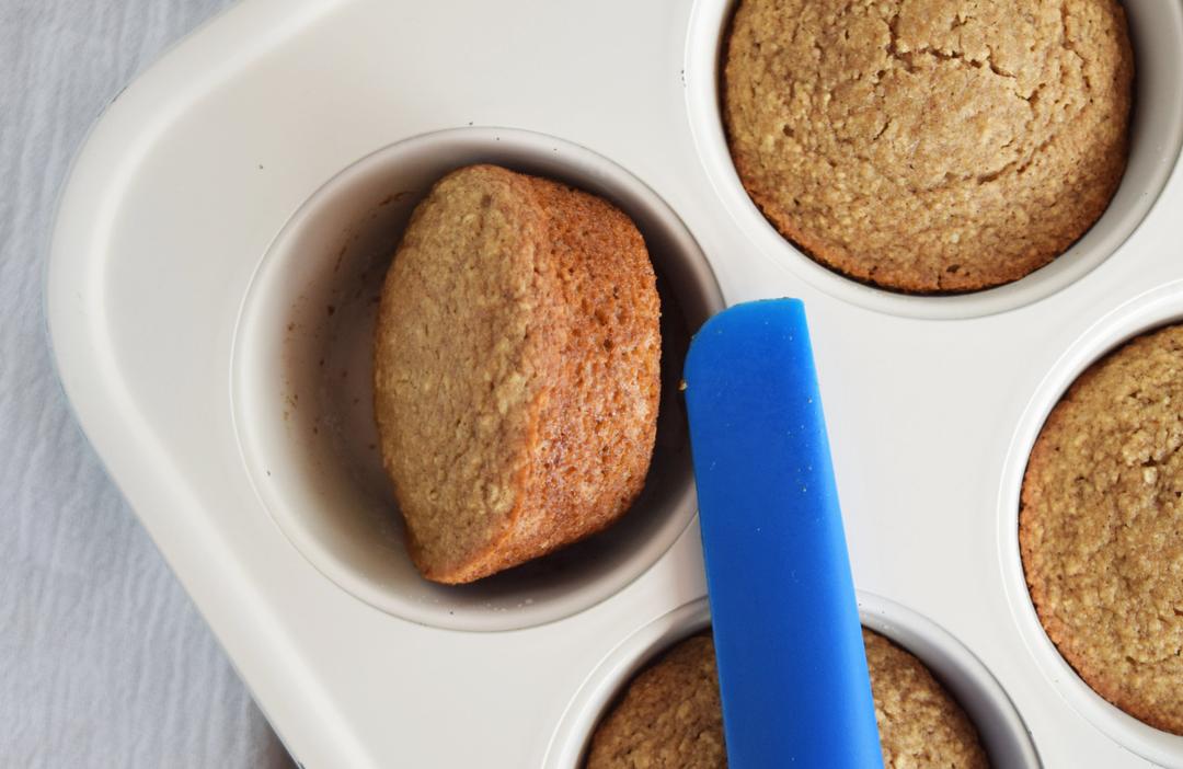 close up of banana muffins in muffin tin with spatula