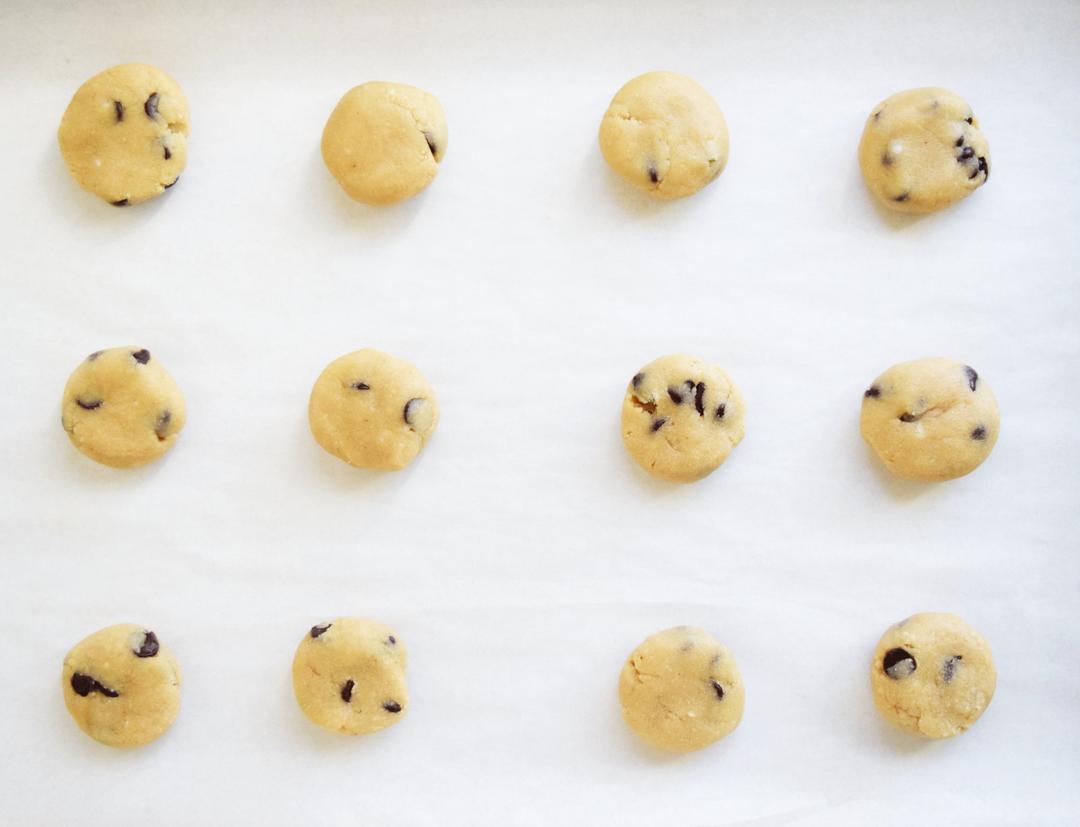 Unbaked chocolate chip cookies on a cookie sheet