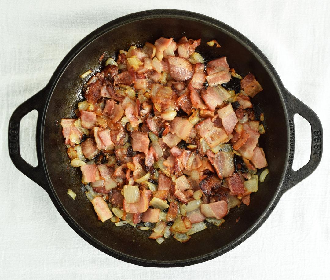 cooked bacon and onion in a cast iron skillet