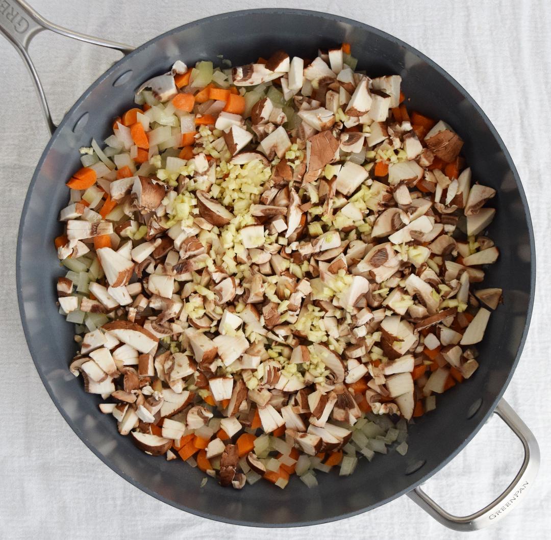 chopped onions, mushrooms, garlic, and carrots in a saute pan