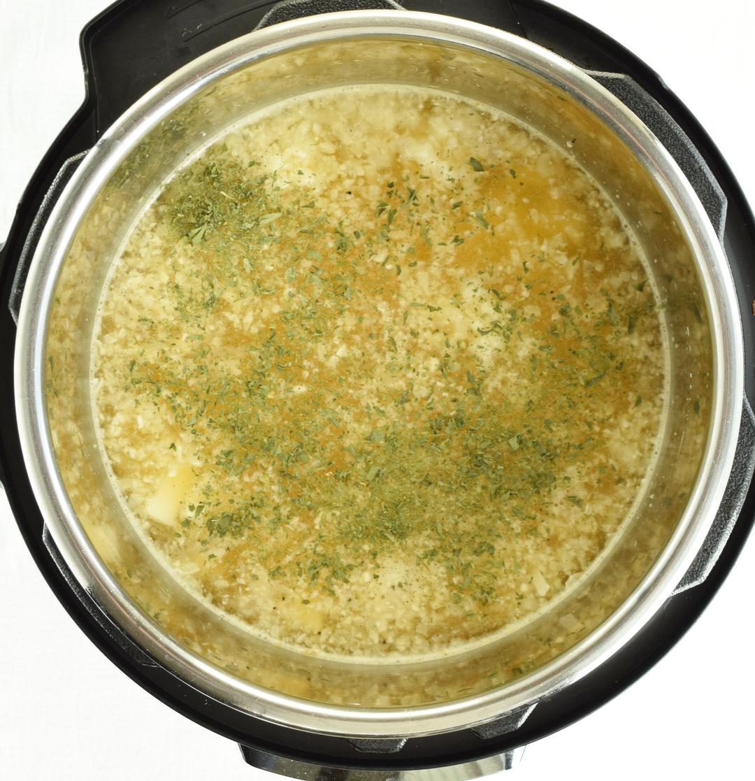 Ingredients added to Instant Pot chopped potatoes, frozen cauliflower rice, chicken broth, water, chicken bouillon, salt, garlic powder, dried parsley, and black pepper in an Instant Pot